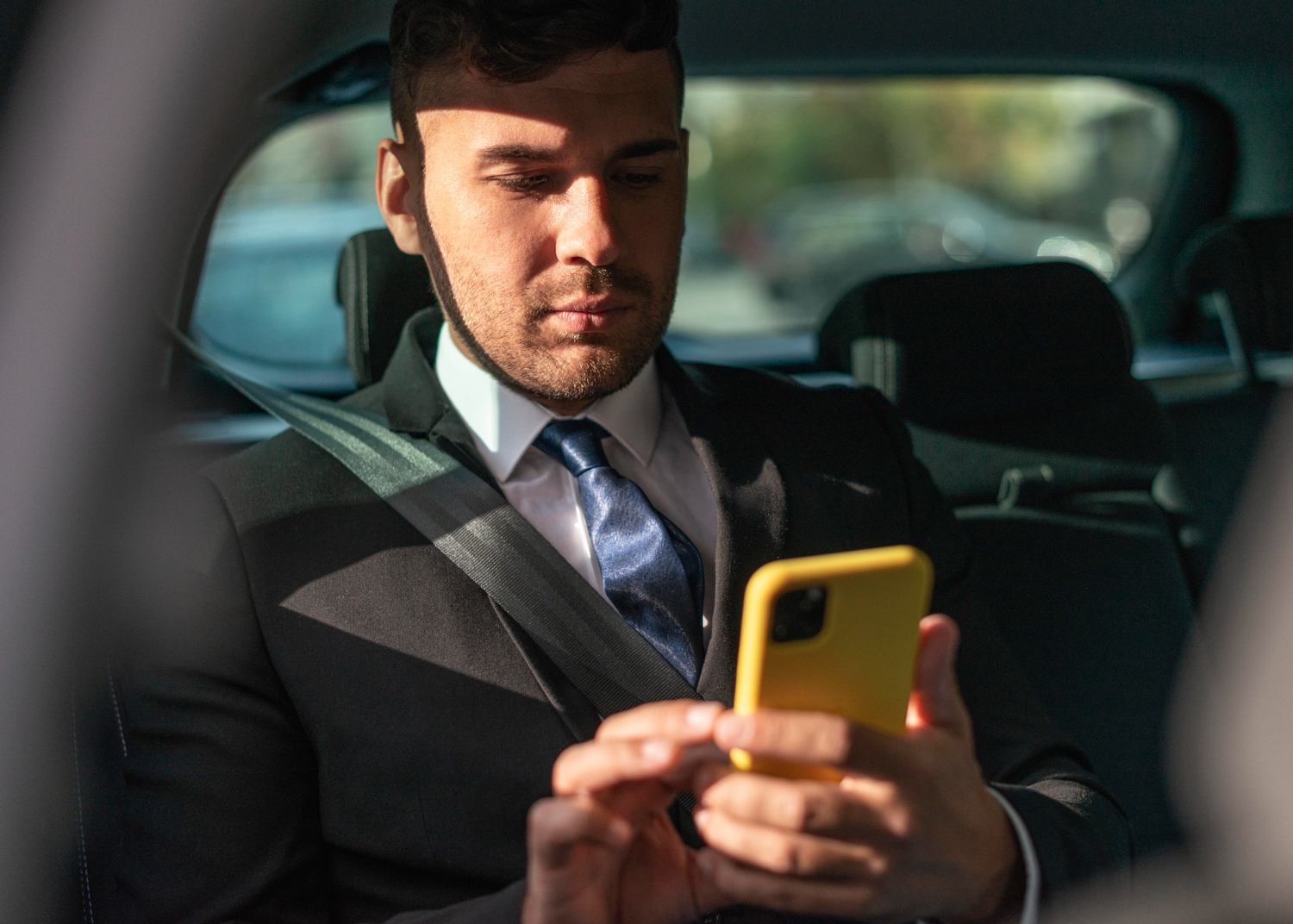 man sitting in a uber taxi using a mobile phone